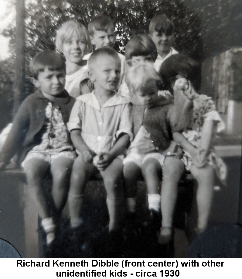 Black and white photo of Richard Kenneth Dibble, about age 5, wearing a wide-collared shirt and shorts, sitting with several other unknown children on the back of a wagon.